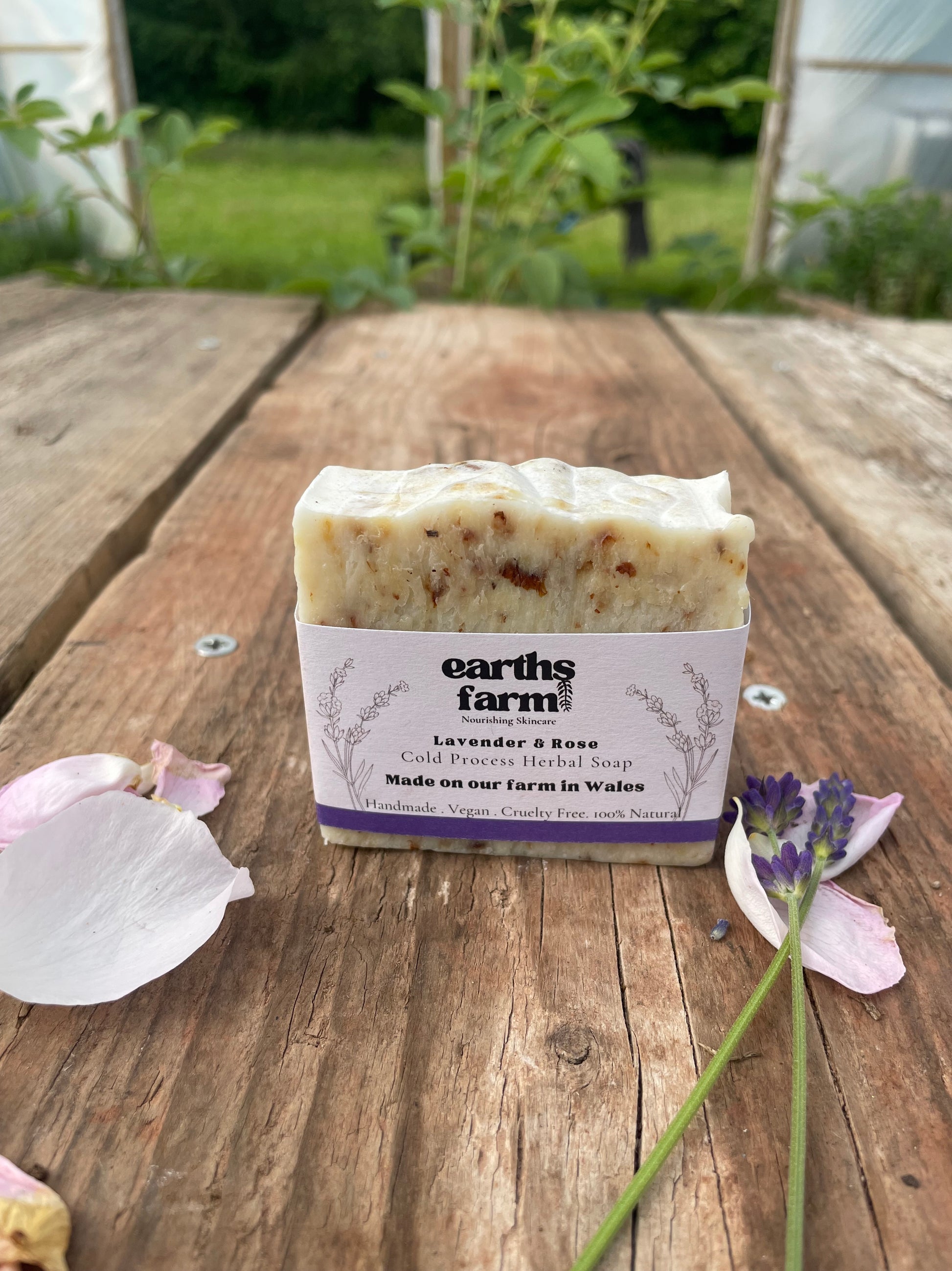 Bar of soap with a label on a wooden surface, surrounded by flowers